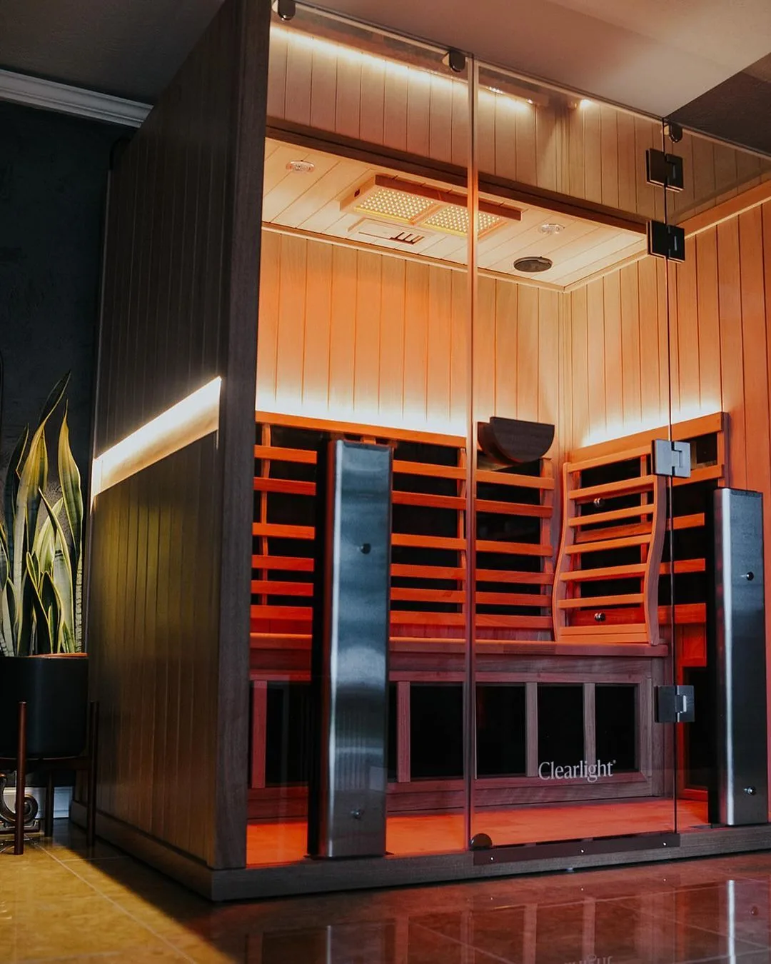 A Clearlight Sanctuary full spectrum infrared sauna glowing in a dark room